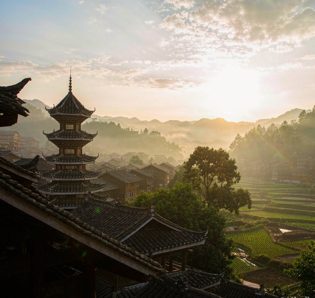 Wooden drum tower and terraced fields in the mist at Zhaoxing Dong village, Guizhou, China